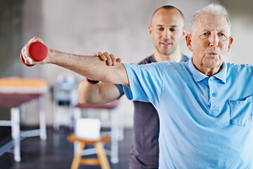 Physio one lift at a time. Shot of a physiotherapist helping a senior man with weights.