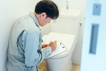 トイレのチェックをする作業着の男性
 - obrazy, fototapety, plakaty