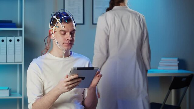 EEG topographer for examining brain, doctor making electrogram of scalp activity. Researching of brain work, man using gadget wearing electroencephalography headset.