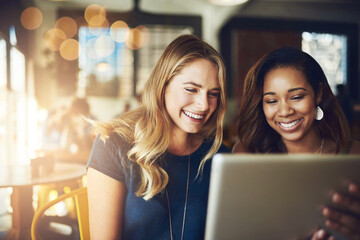 Five star rating for a five star cafe. Cropped shot of girlfriends sharing something on a digital tablet while sitting in a cafe.