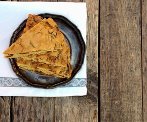The benefits of dried fruit. A piece of homemade Apple pie with chips or slices on a metal plate on a wooden background. Natural food.