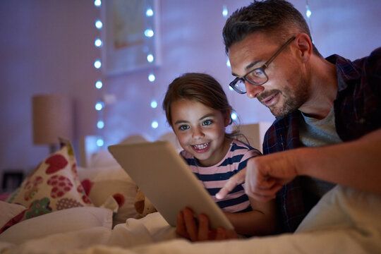 See, they lived happily ever after. Shot of a little girl and her father using a tablet before bedtime.