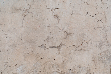 An old shabby wall with cracks. Peeling plaster. Street walls of the old building. Renovation of living quarters. Textured surface, abstract drawing