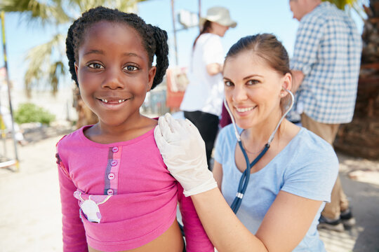 Feeling great thanks to doctor. Shot of a volunteer nurse examining a young patient with a stethoscope at a charity event.
