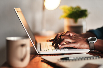 The hard work never ends. Cropped shot of an unrecognizable businessman sitting alone in his home office and working on his laptop.