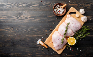 Sliced chicken thighs with skin on a cutting board. Black wooden background. Top view. Copy space