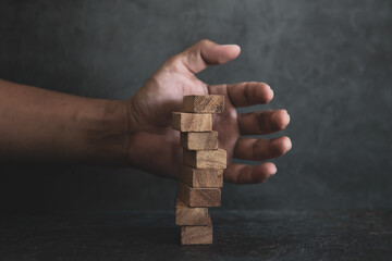 Hand prevent wooden block stack in tower stair step concept of prevent collapse or crash of...