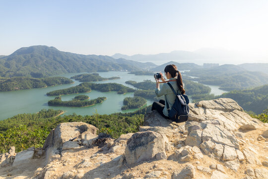 Woman take photo on camera and sit on the top of mountain