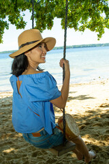 beautiful woman sitting on the swing at the beach