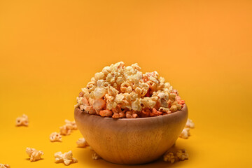Fototapeta na wymiar Delicious popcorn in wooden bowl on yellow background.