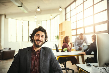 Im into innovation. Cropped portrait of a handsome young businessman sitting in the office with his colleagues in the background.