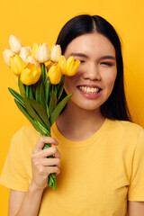 woman with Asian appearance in a yellow t-shirt t-shirt with a bouquet of flowers holiday Monochrome shot