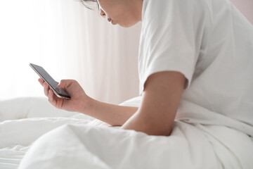 sleepy young man using smartphone on the bed 