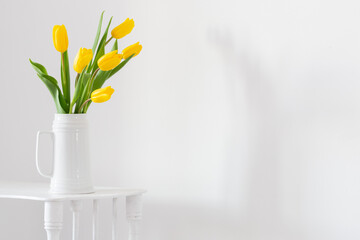 yellow tulips in vase on white background