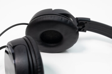 Black headphones on white desk close up on ear pads. 