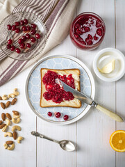 Homemade butter sandwiches with raspberry jam on a white wooden background.