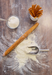 we prepare homemade cakes. flour on the table, sugar, spatula, rolling pin and straw in a cup
