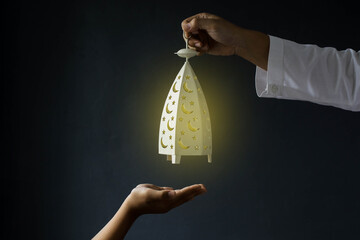 Ramadan kareem background concept. Muslim hand giving Ramadan lantern decorations held on black...