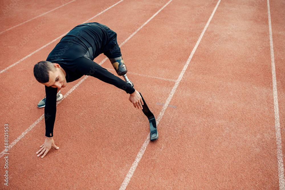 Poster A fit sportsman with prosthetic leg working out at stadium on running track.