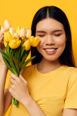 Charming young Asian woman with a bouquet of yellow flowers romance yellow background unaltered