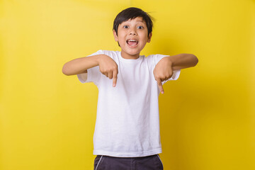 Happy little boy with pointing down gesture isolated on yellow background
