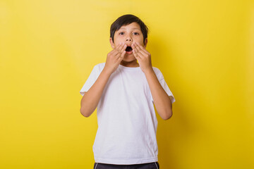 Little boy in casual style surprised looking at camera isolated on yellow background