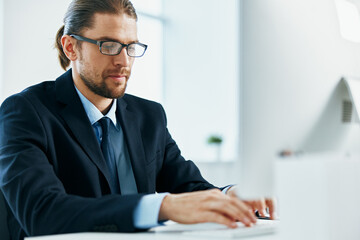 business man with glasses in a suit works at the computer in the office