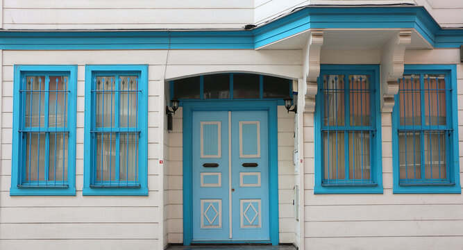 Cute Wooden White House With Blue Entrance Door And Windows.