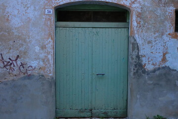 old green wooden door of a traditional italian stone building