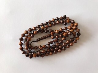 99 Islamic prayer beads on a white background for ramadan, eid adha, eid fitr, flyer islamic and etc . close up of wood tasbih