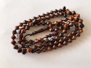 99 Islamic prayer beads on a white background for ramadan, eid adha, eid fitr, flyer islamic and etc . close up of wood tasbih