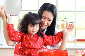 Happy smiling beautiful young mom with her little adorable child daughter girl opening surprise red...