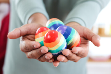 Rainbow Easter eggs on hands, LGBT hands holding colorful eggs painted in rainbow colors of flag of LGBTQ gays and lesbians.