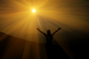 A man raises a cross on a mountain, the sun is shining on him.