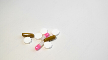 White tablets and multi-colored capsules scattered on a white background