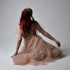 Full length portrait of pretty female model with red hair wearing glamorous fantasy tulle gown,...