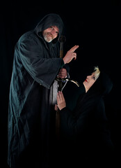 Absolution: An elderly warrior monk with a sword blesses a beautiful kneeling woman. Historical...