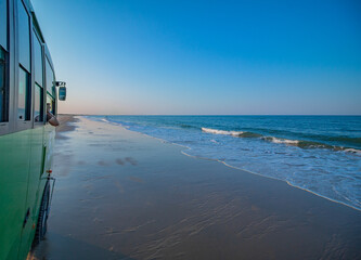 Atlantic Ocean during a sunny day, seen from an all-terrain truck driving along a beach, during a...