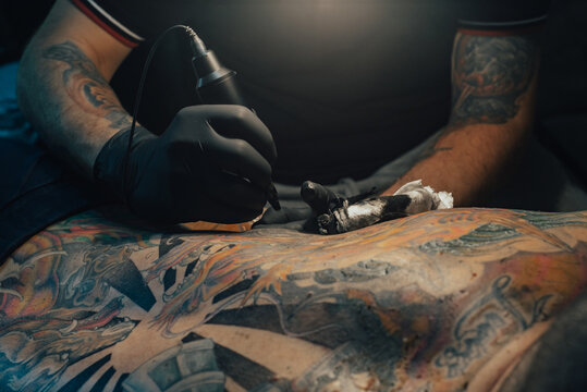 Tattoo artist holding a machine while working in a studio