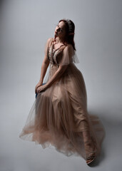  Full length portrait of pretty female model with red hair wearing glamorous fantasy tulle gown,...