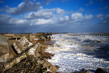Climping Beach in West Sussex, Southern England on the English Channel with waves braking on the rocks after Storm Eunice with old sea defences already damages holding the sea back.