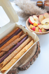 Natural fruit marshmallow in a white box on the background of a plate with apples and candles