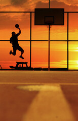 a basketball player in a jump scores a ball into the ring against the background of a bright summer sunset