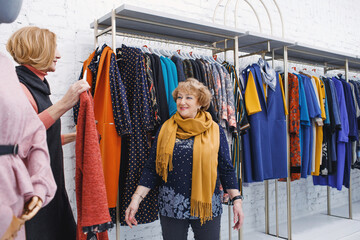 two mature women are choosing fashionable clothes in a clothing store.