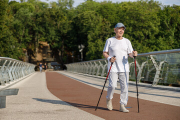 Senior sportsman practices Nordic walking training on empty footbridge