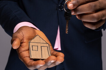black man hands holding cardboard house and key