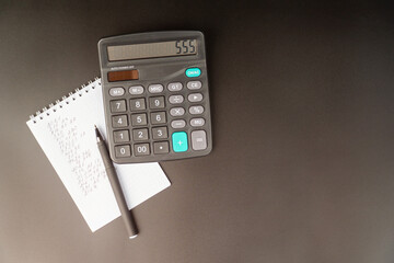 flat view of desktop including pen, note, calculator on black