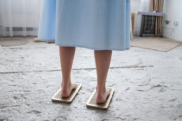 Female legs in a blue dress on a sadhu board with nails