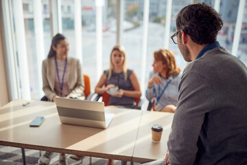 A young businessman is enjoying in a coffe break with his female colleagues in a commission during an interview for a new job position. Business, people, company