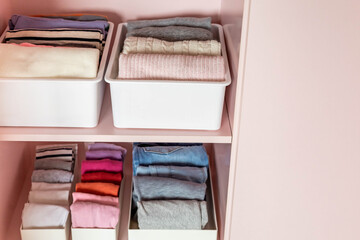 Closeup shelves pink female childish closet with neatly folded clothes Marie Kondo vertical storage